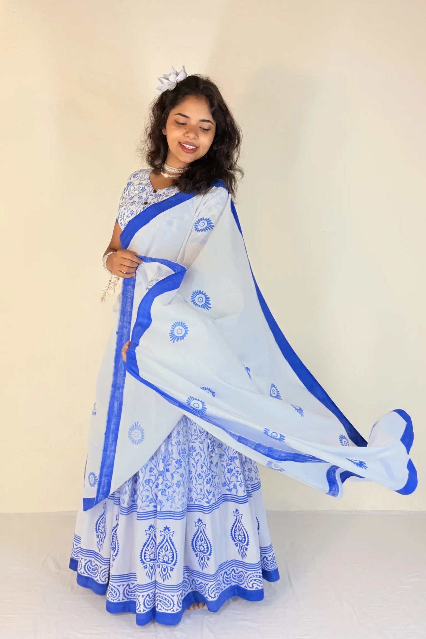 Woman wearing a white Gopi Dress with blue patterns against a plain background