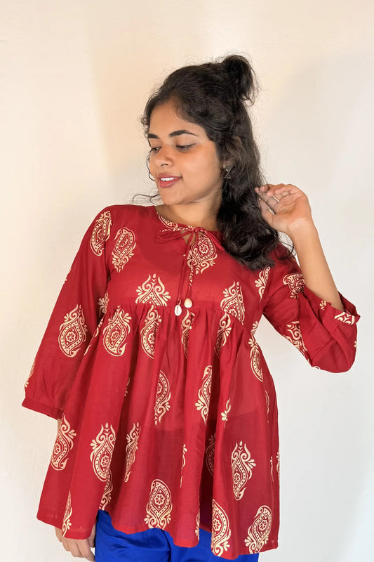 Woman wearing a red patterned blouse against a plain background