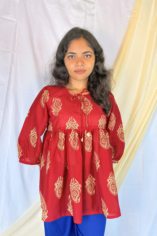 Woman wearing a red embroidered top with a white background