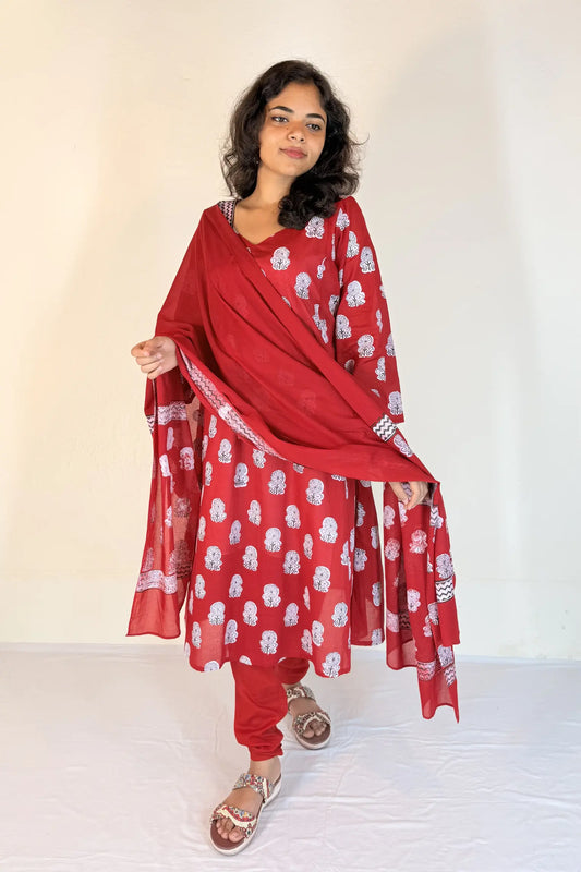 Woman wearing a red traditional outfit with white patterns on a plain background