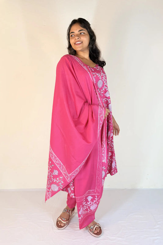 Woman wearing a pink traditional outfit with white patterns on a plain background