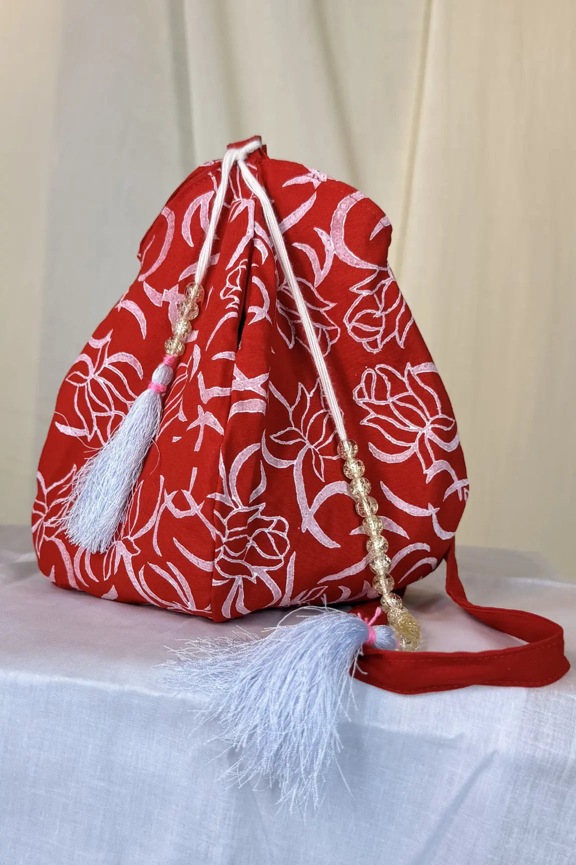 Red drawstring bag with white floral patterns on a white surface