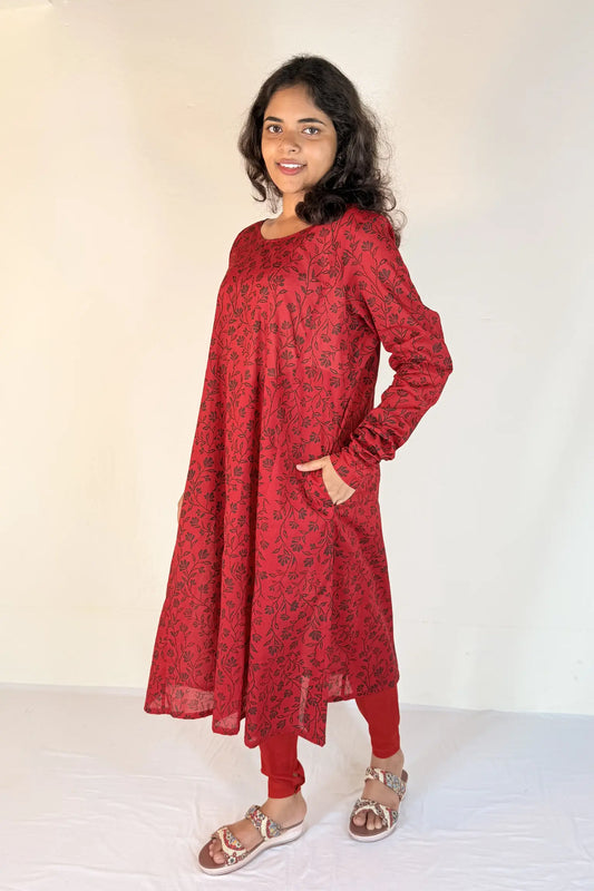 Woman wearing a red patterned dress with long sleeves on a white background