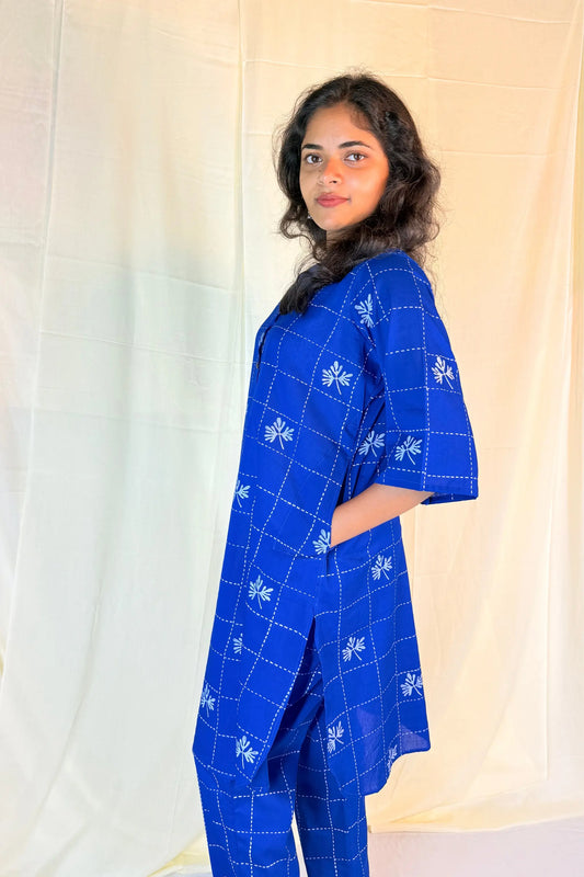 Woman wearing a blue checkered outfit with a plain background