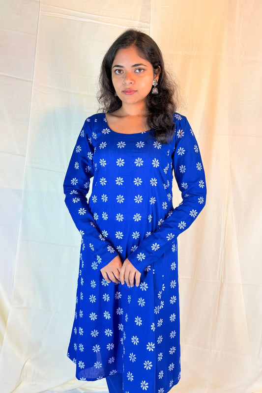 Woman wearing a blue dress with white floral patterns against a light background
