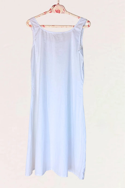 A light blue sleeveless slip dress hanging on a floral-patterned wooden hanger against a plain off-white background.