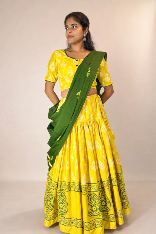 Woman wearing a yellow traditional outfit with a green sash on a beige background