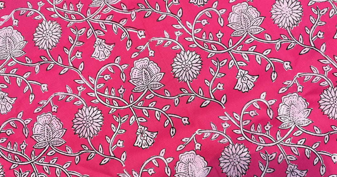 Bright pink floral block print fabric featuring intricate hand-drawn vines, blooming flowers, and delicate leaf motifs in soft white and black detailing.