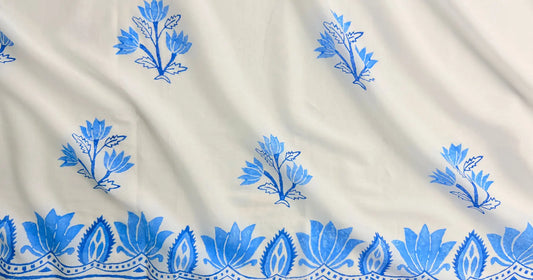 White fabric with blue floral block prints and a decorative blue border along the bottom edge.