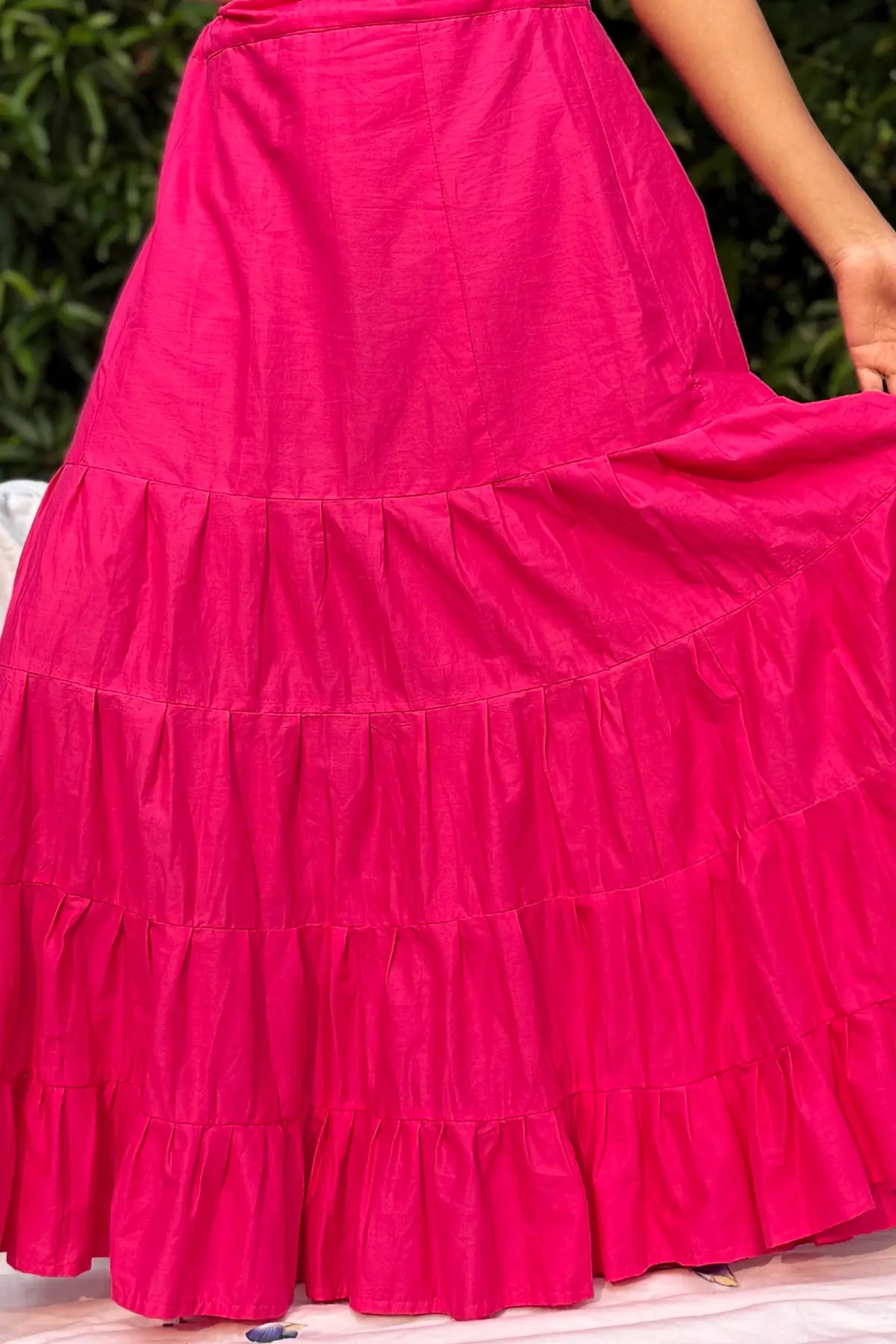 Bright pink cotton petticoat with layered pleated panels, worn by a model outdoors in natural light.