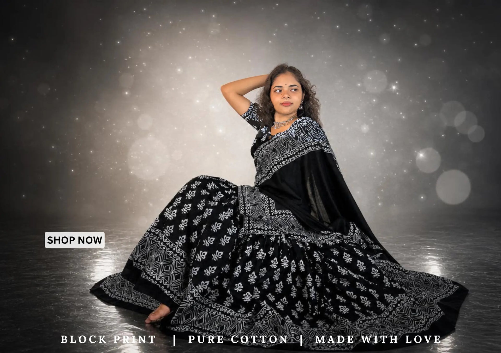 Woman in a black and white patterned saree against a dark background with 'Shop Now' text.