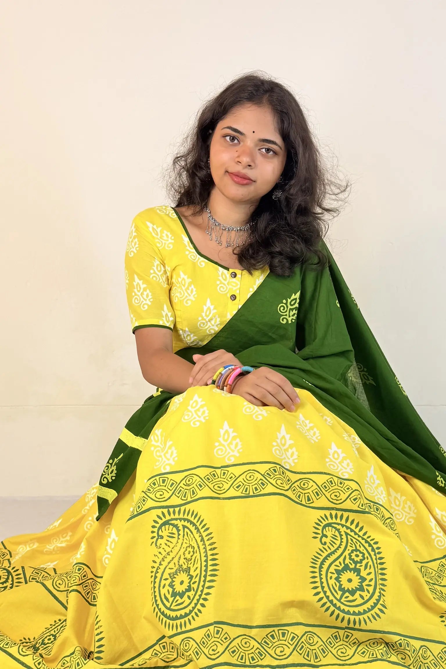 Woman wearing a yellow and green Gopi Skirt Set with a white background