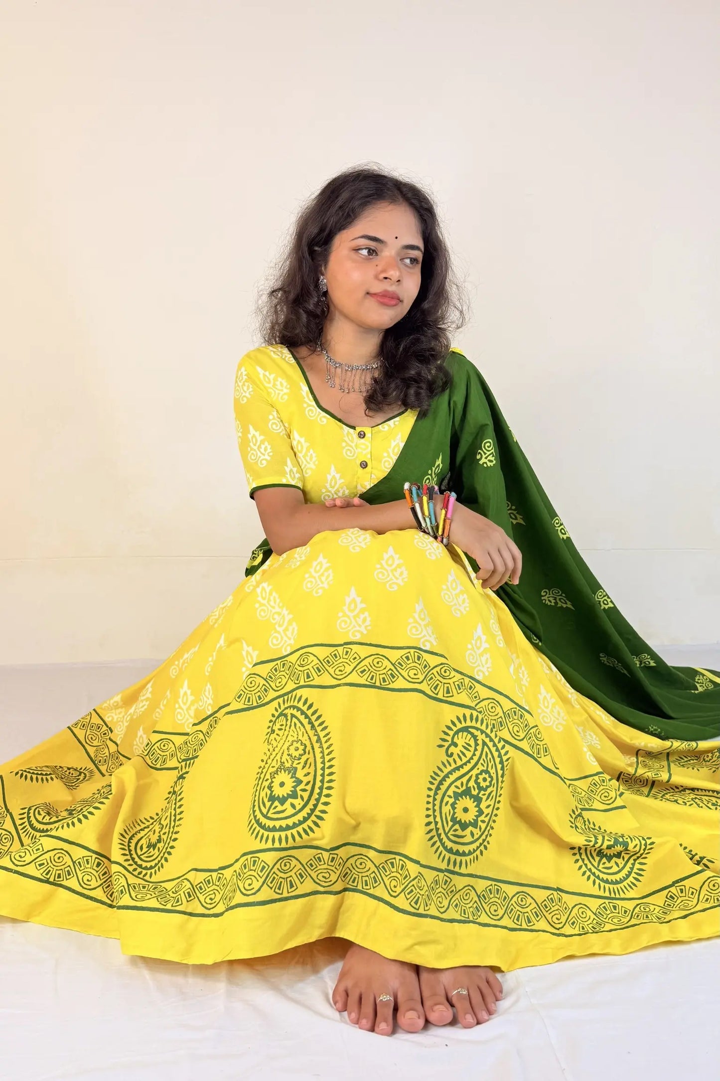 Woman wearing a yellow and green traditional outfit with a white background