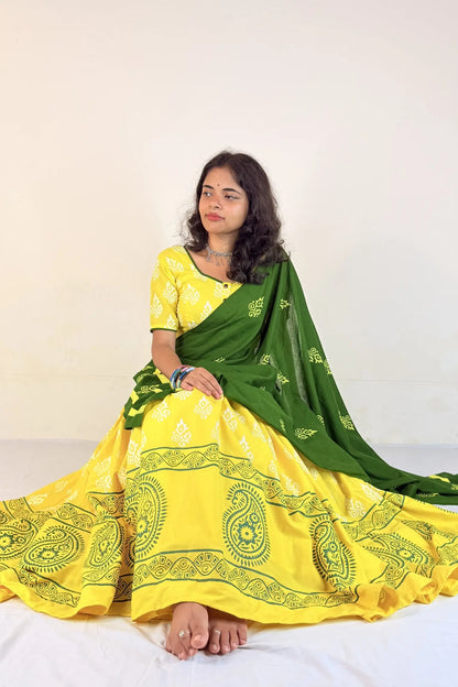 Woman wearing a yellow Gopi Skirt Set with green border on a white background