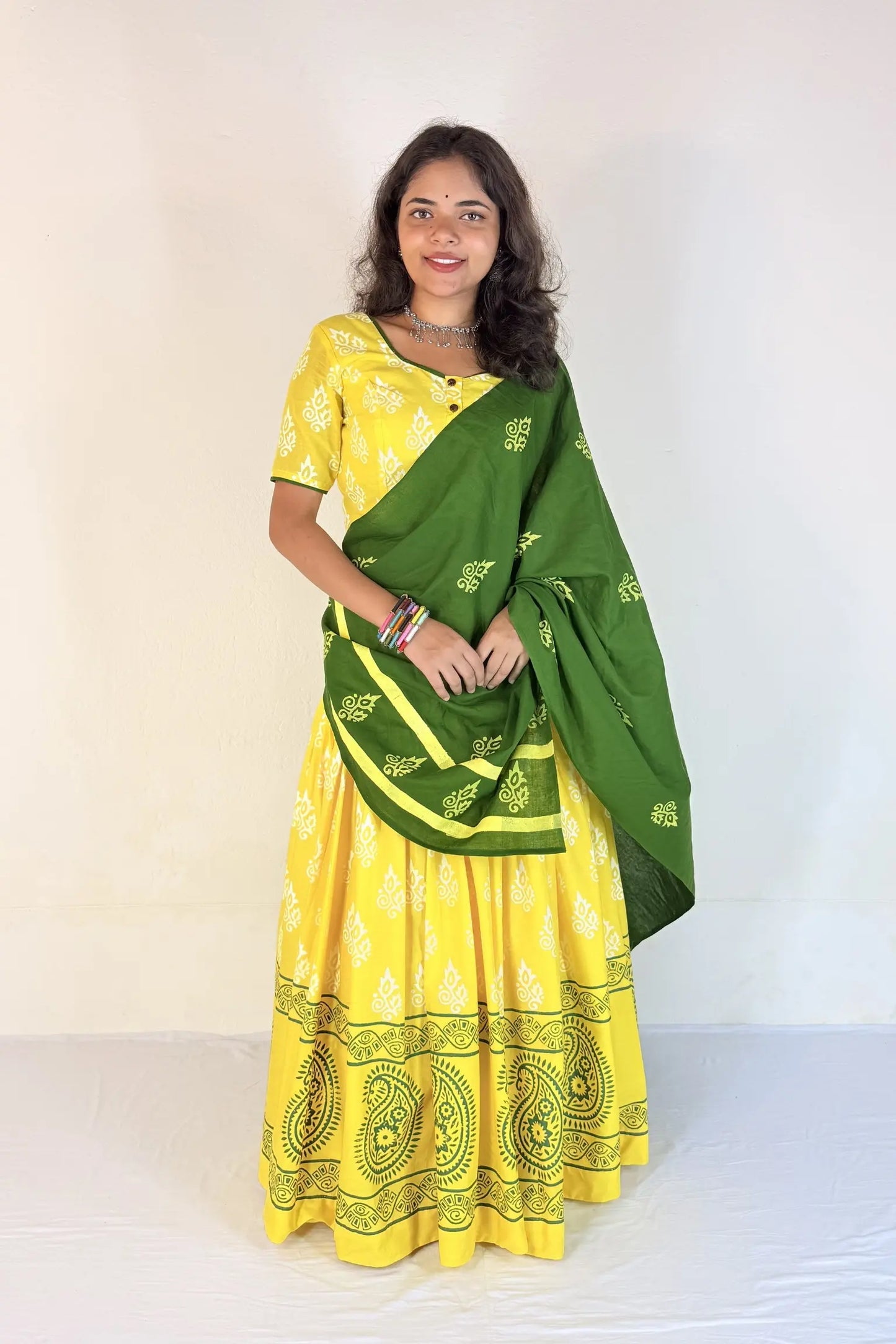 Woman wearing a yellow and green traditional outfit with a white background