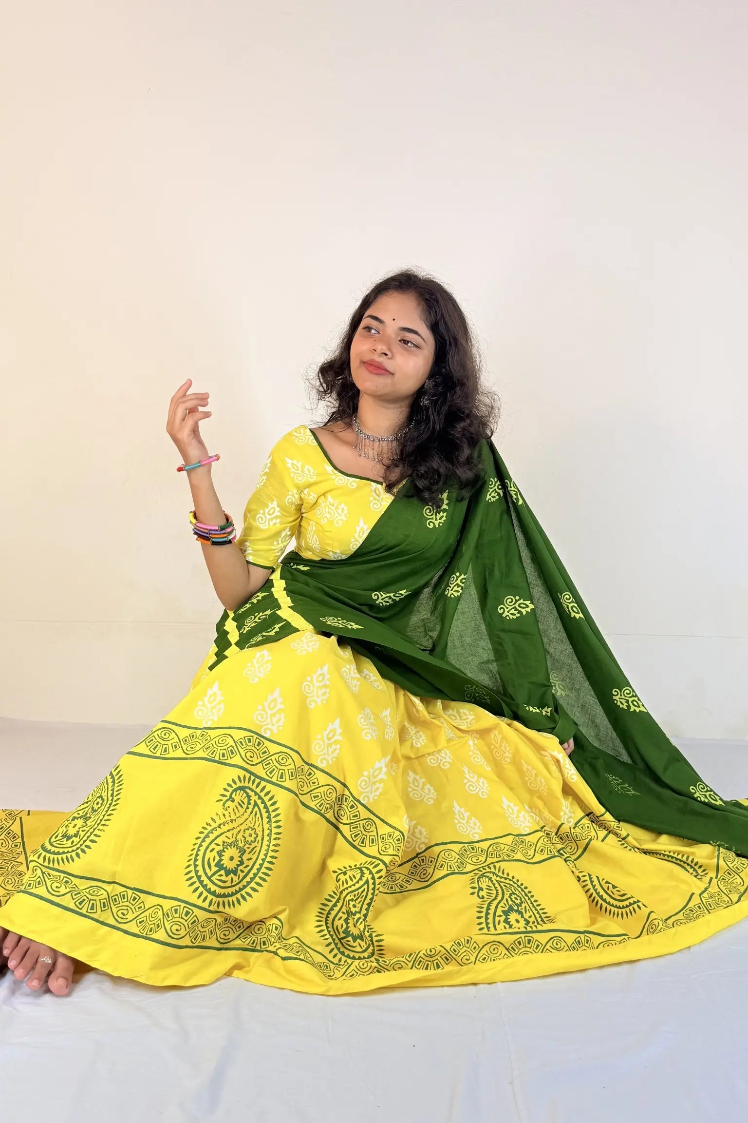 Woman wearing a yellow and green traditional outfit with a white background