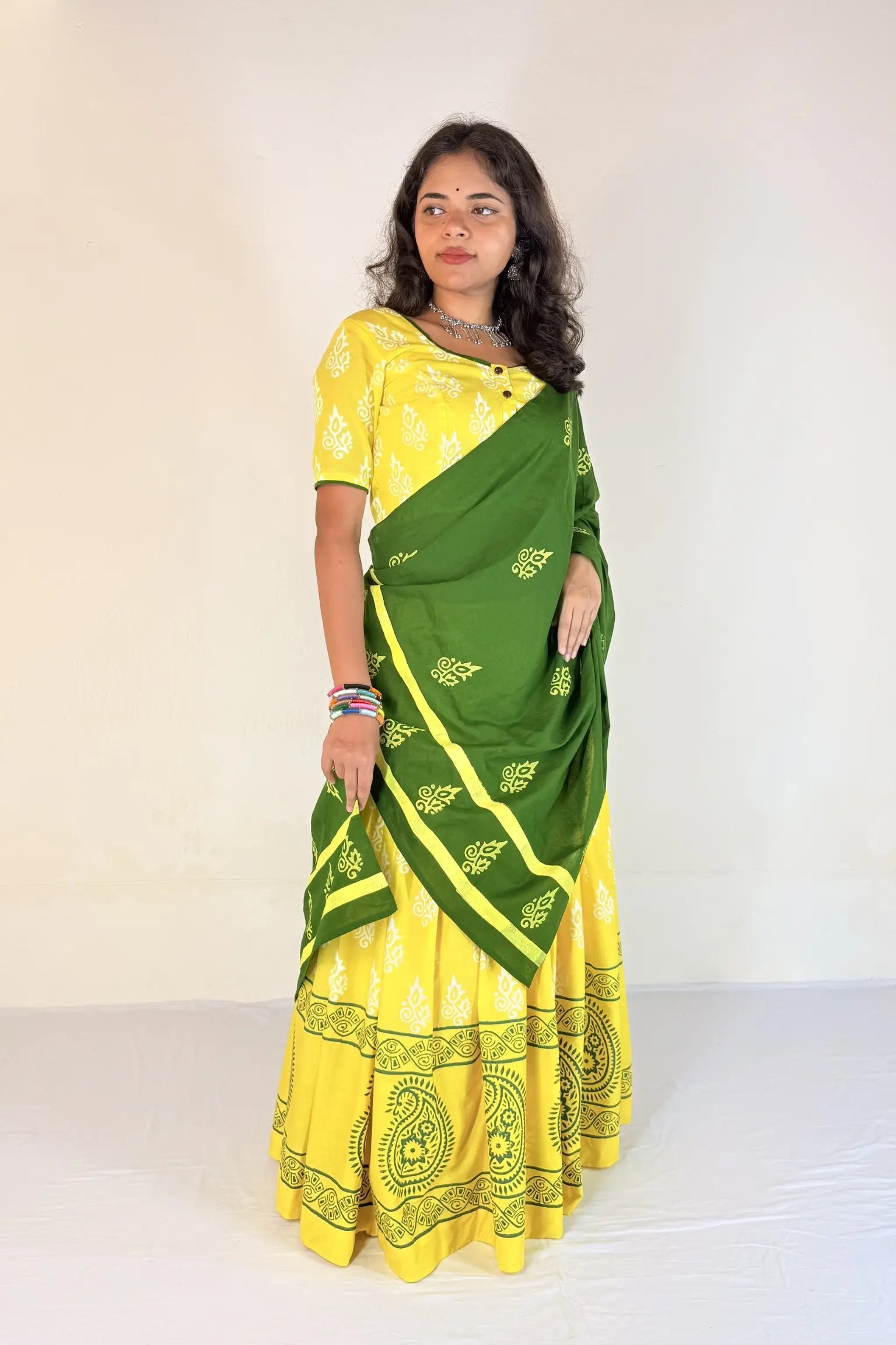 Woman wearing a green and yellow Gopi Skirt Set against a white background