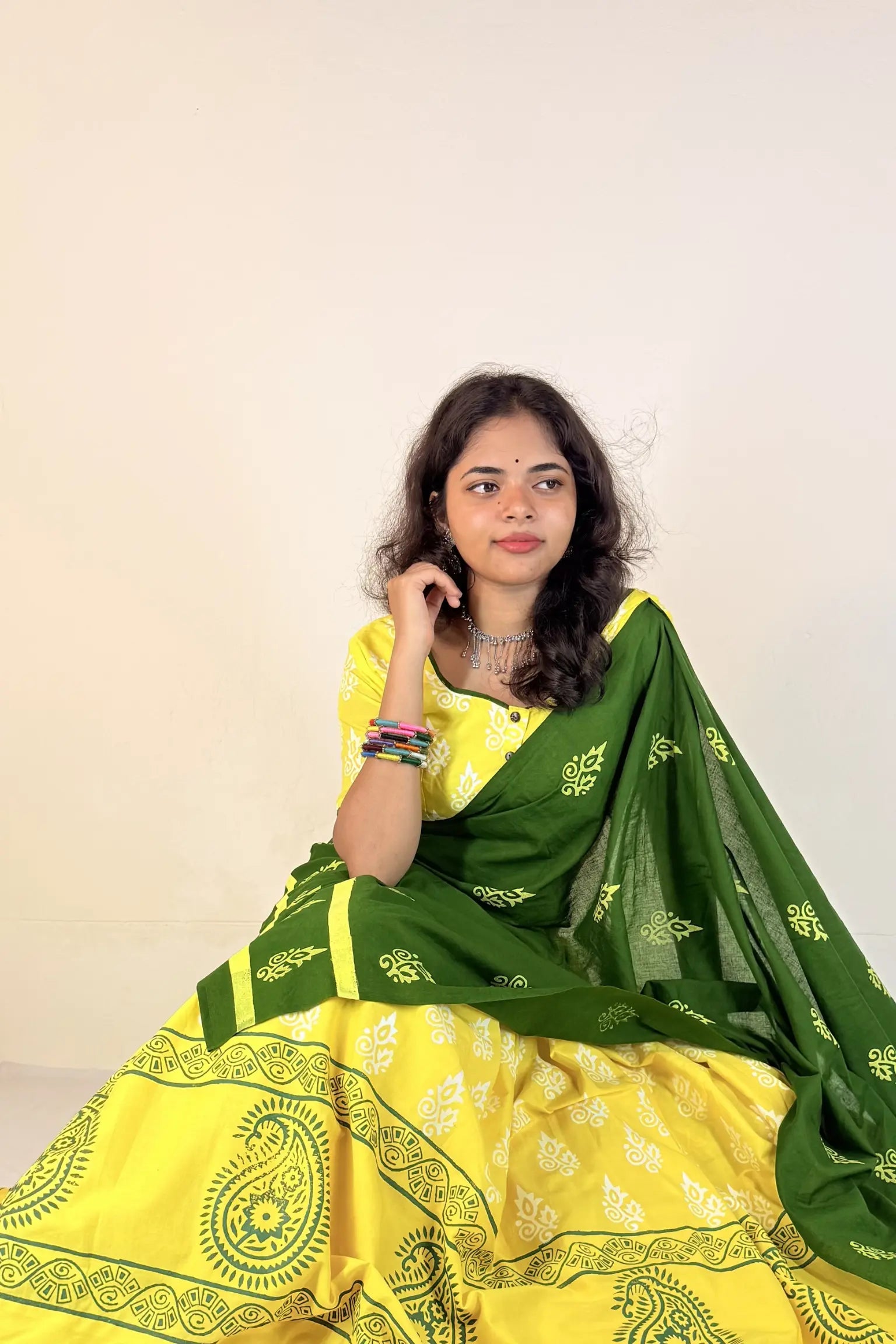 Woman wearing a yellow and green Gopi Skirt set  with a white background