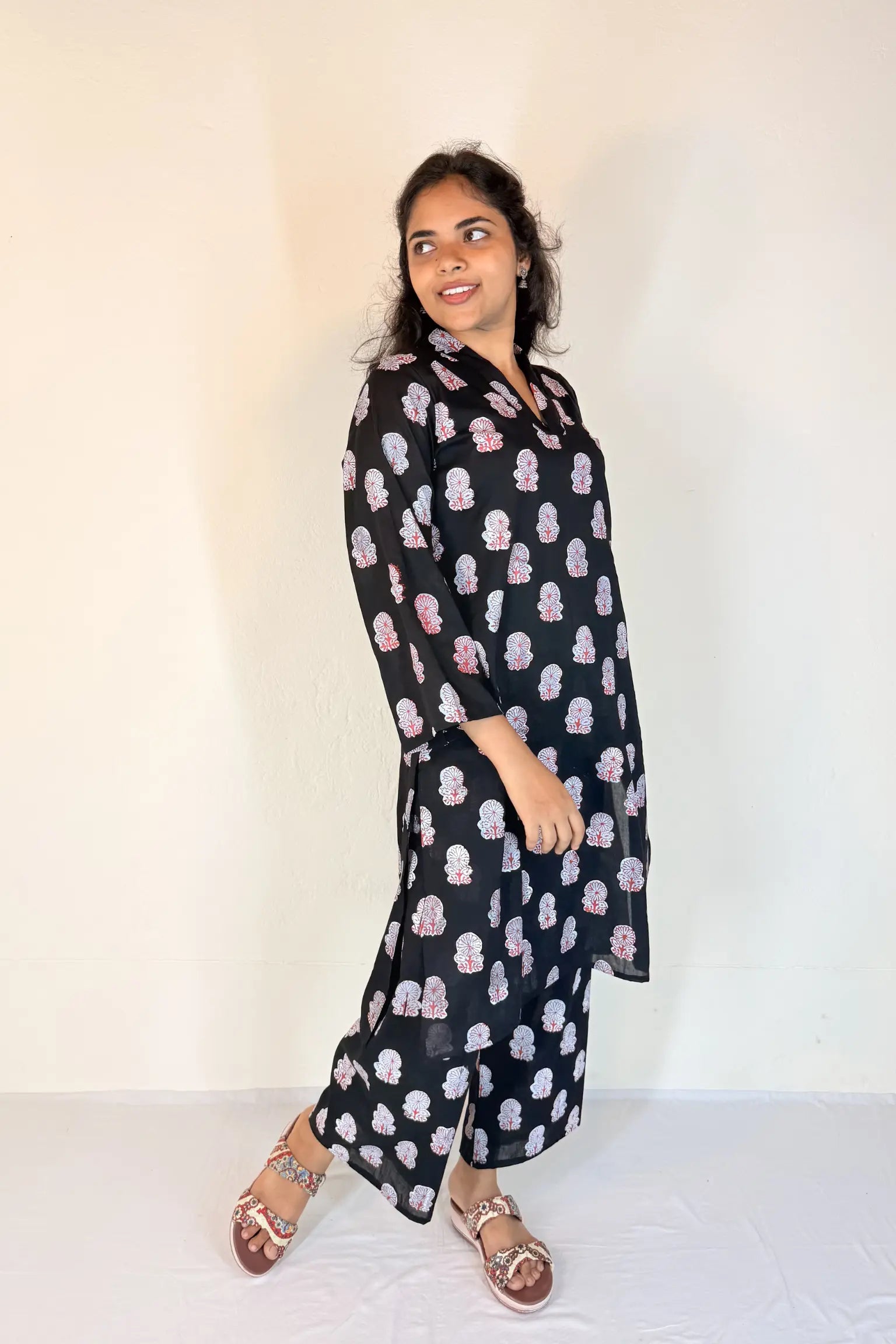 Woman wearing a black floral patterned dress against a white background