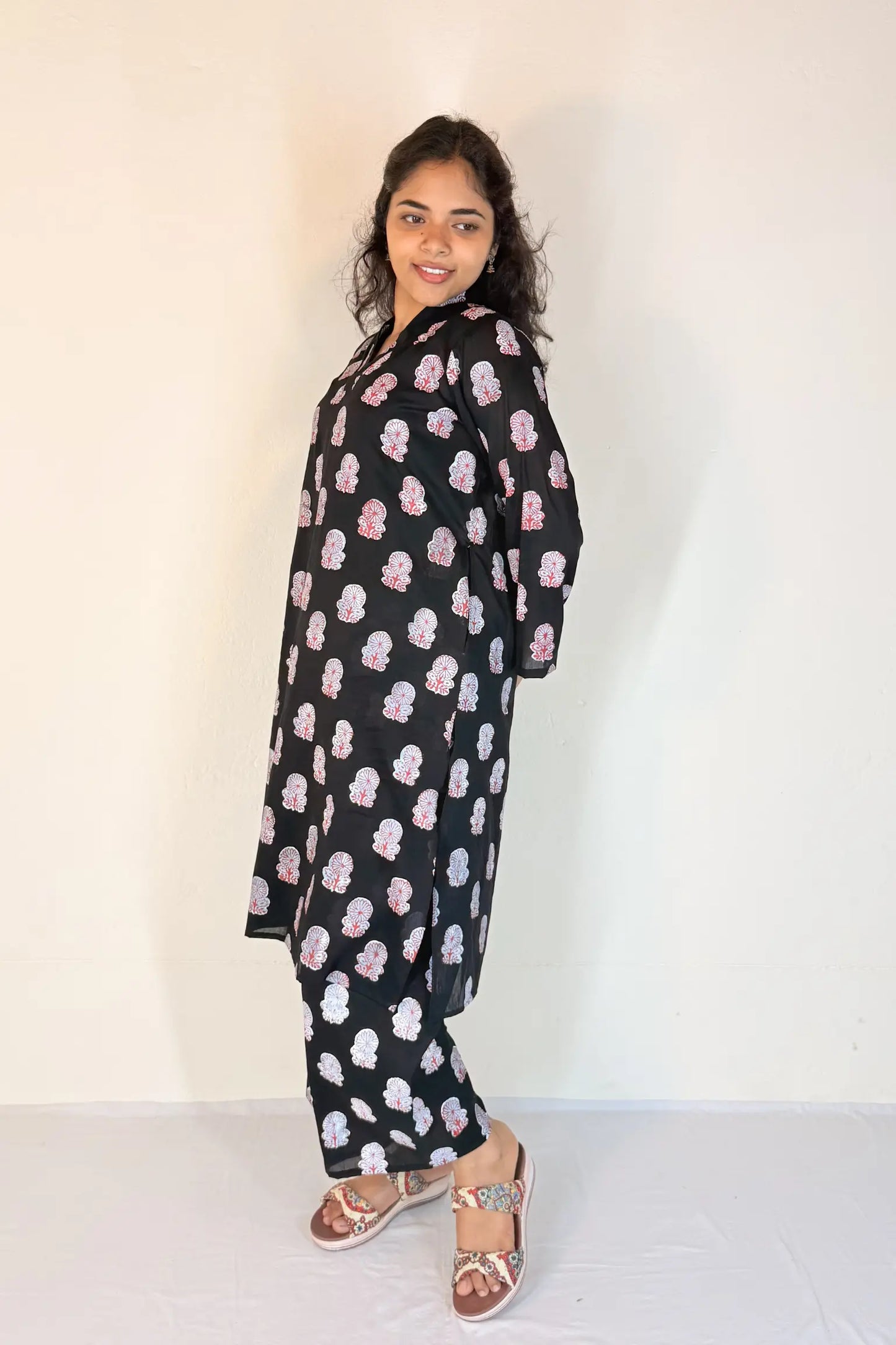 Woman wearing a black outfit with pink floral patterns against a white background