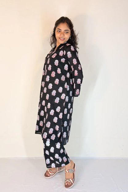 Woman wearing a black outfit with pink floral patterns against a white background