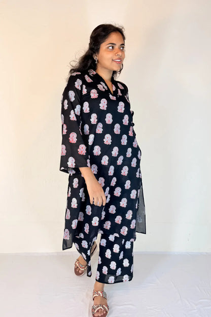 Woman wearing a black floral dress against a white background