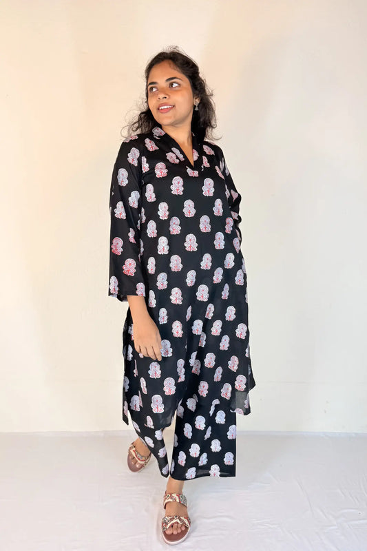 Woman wearing a black dress with pink floral pattern against a white background
