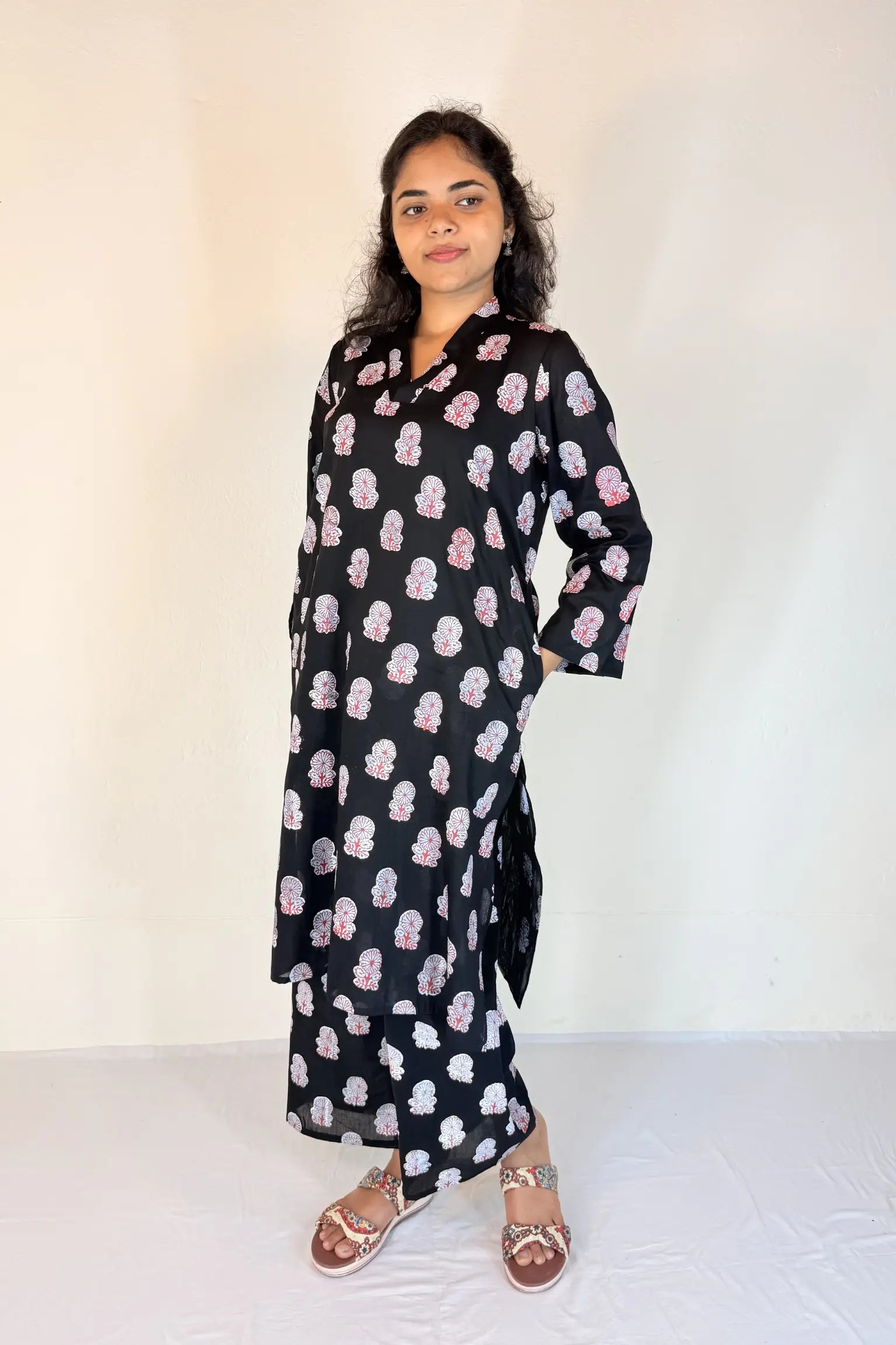 Woman wearing a black dress with pink floral pattern against a white background