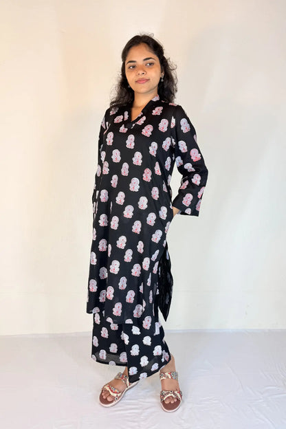 Woman wearing a black dress with pink floral pattern against a white background