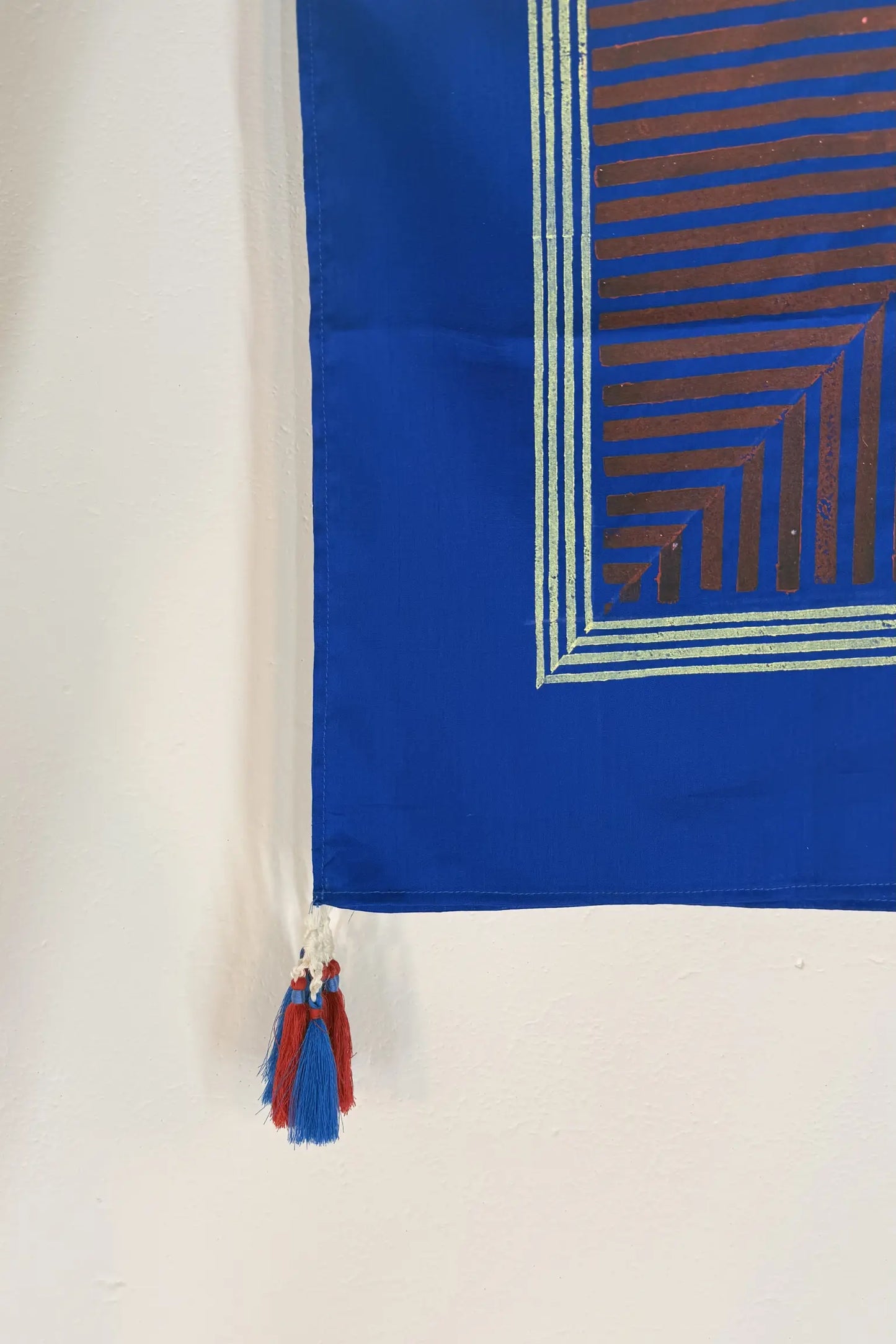 Blue cotton scarf with gold geometric block print and handcrafted blue and red tassel detailing at the edge