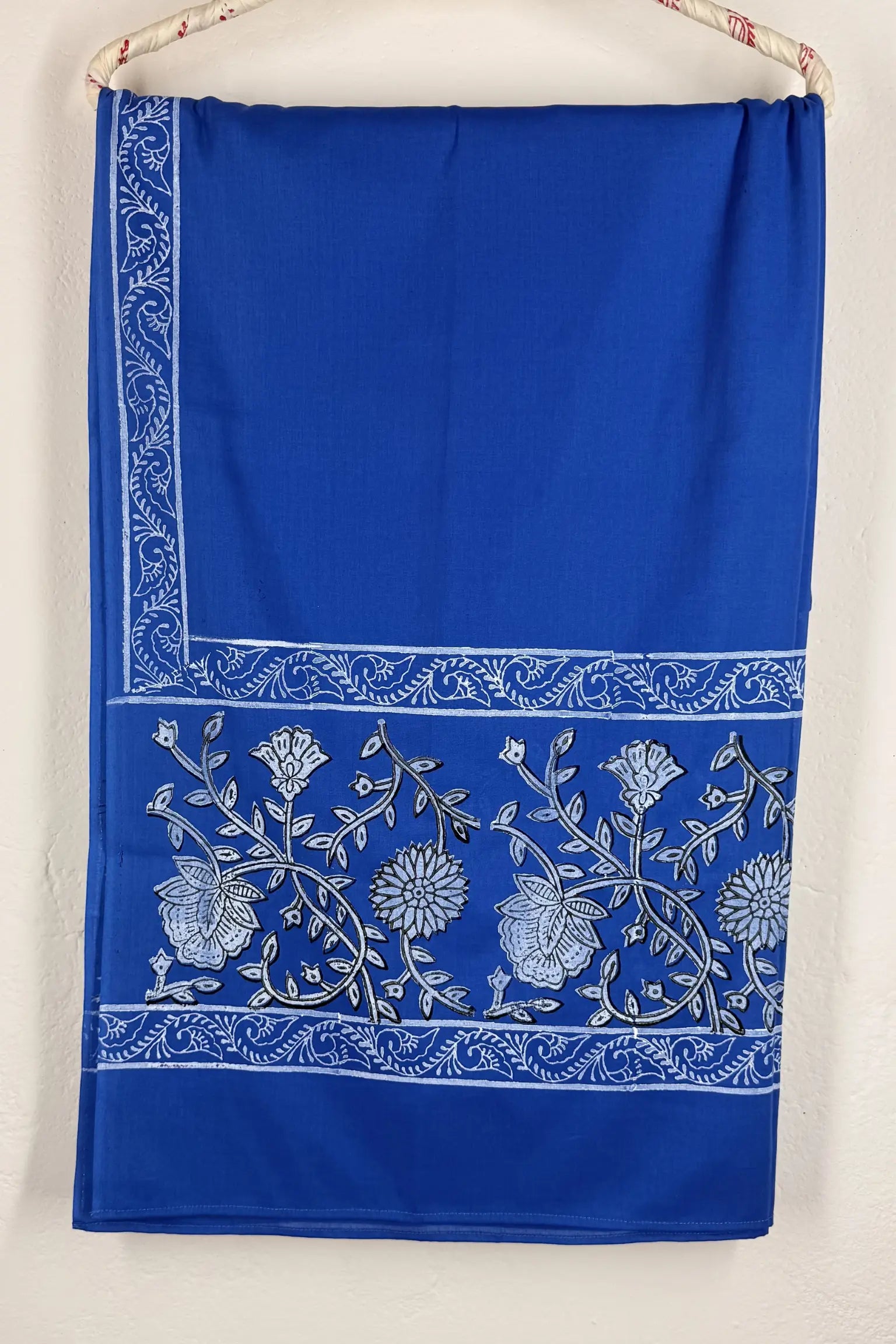 Blue fabric with white floral embroidery on a beige background