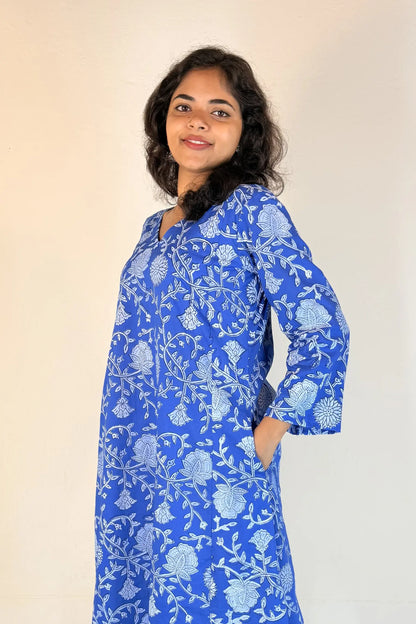 Woman wearing a blue floral dress against a plain background