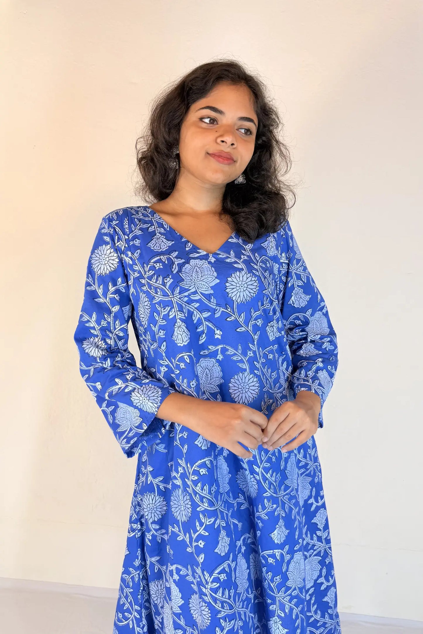 Woman wearing a green dress with yellow floral patterns on a white background
