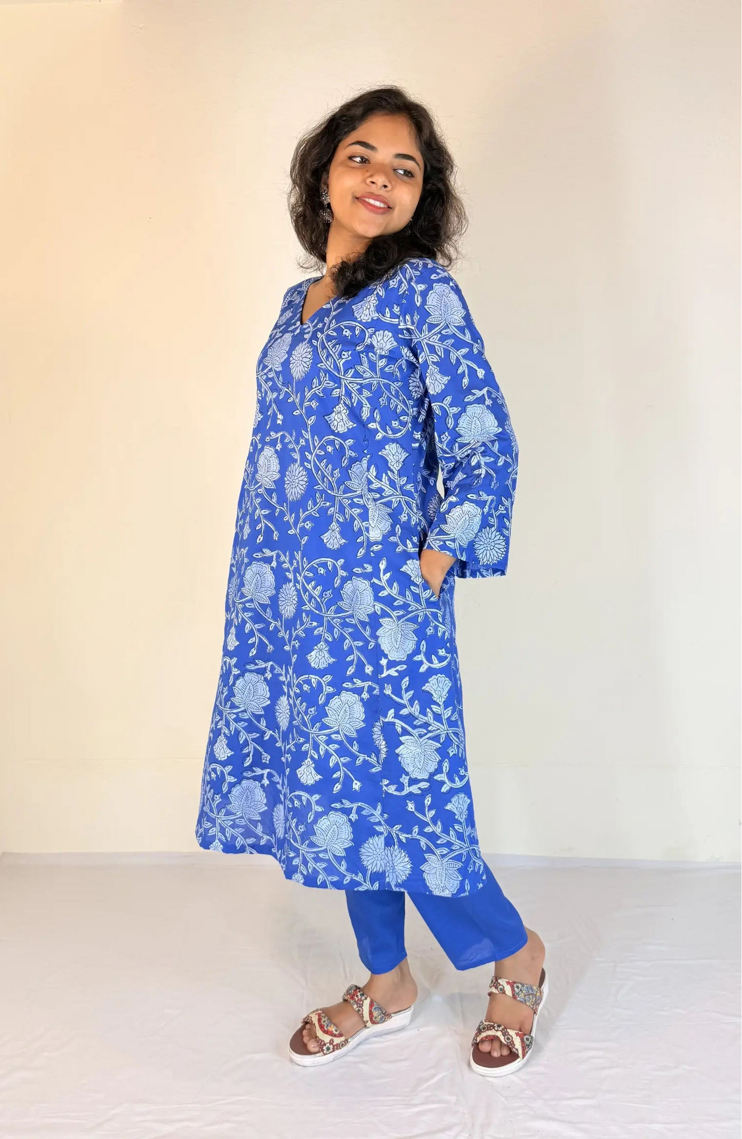 Woman wearing a blue floral dress against a white background