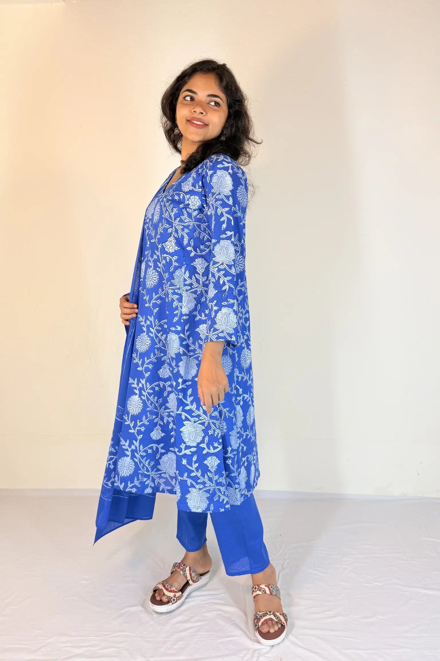 Woman wearing a blue floral kurta with white flowers on a plain background