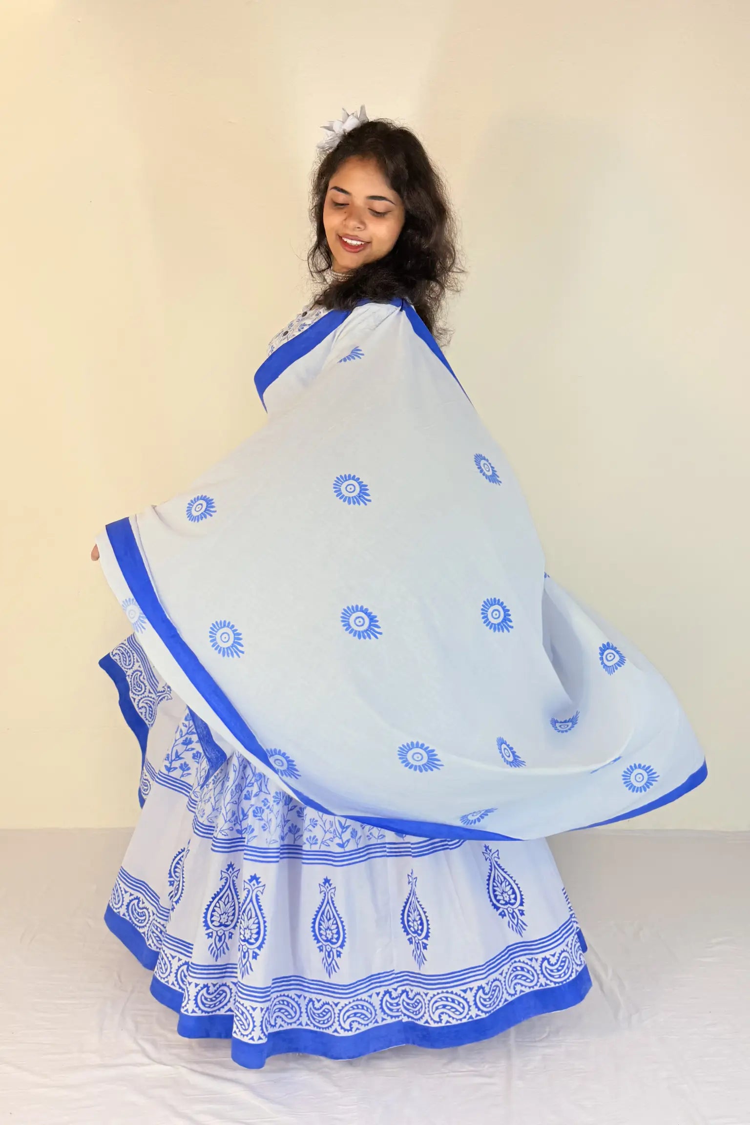 Woman wearing a white Gopi Dress with blue patterns against a beige background