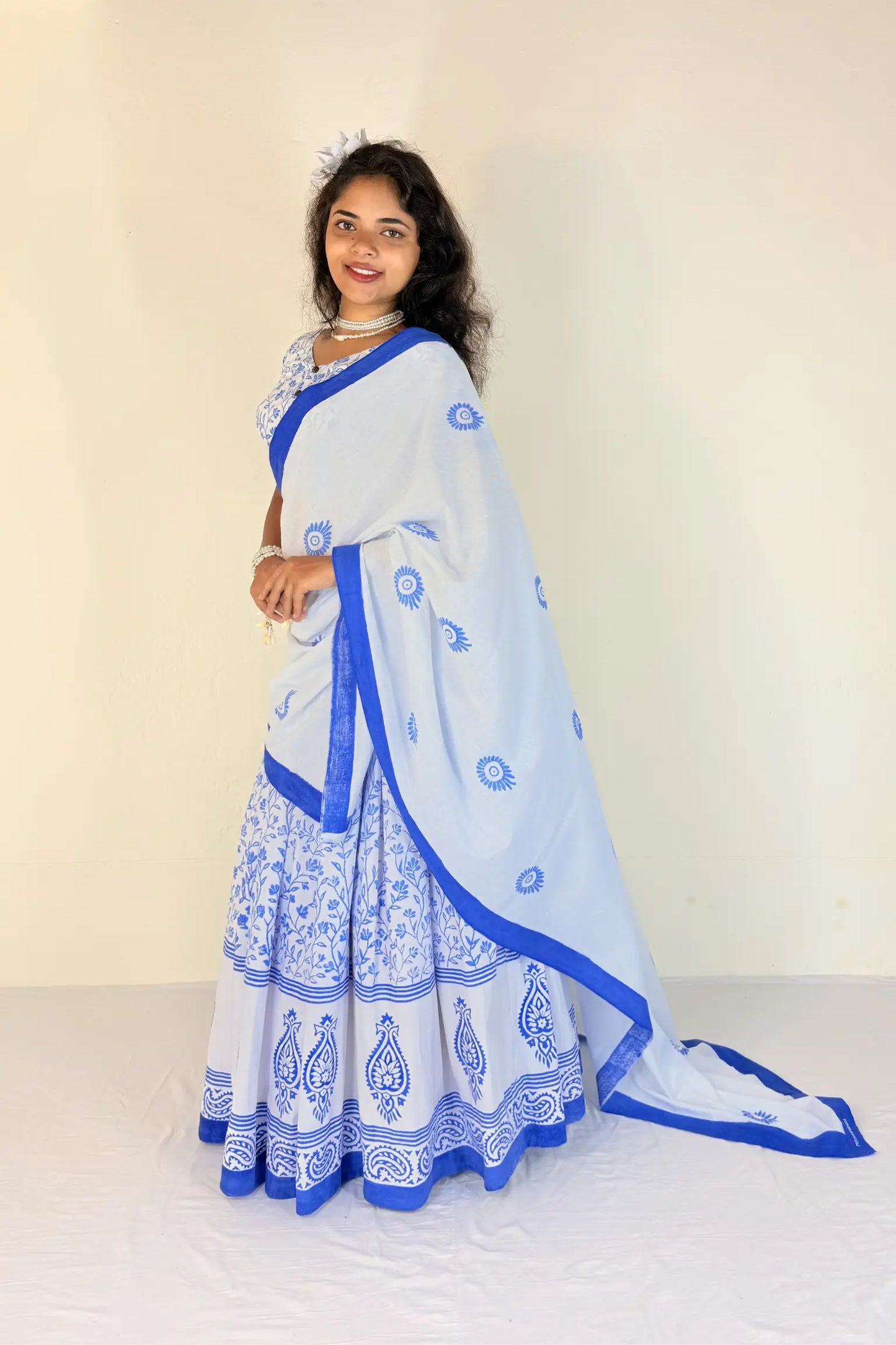 Woman wearing a white Gopi Dress with blue patterns against a plain background