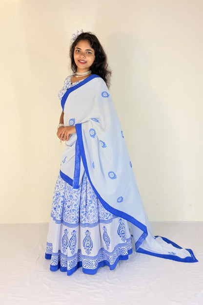 Woman wearing a white Gopi Dress with blue patterns against a plain background