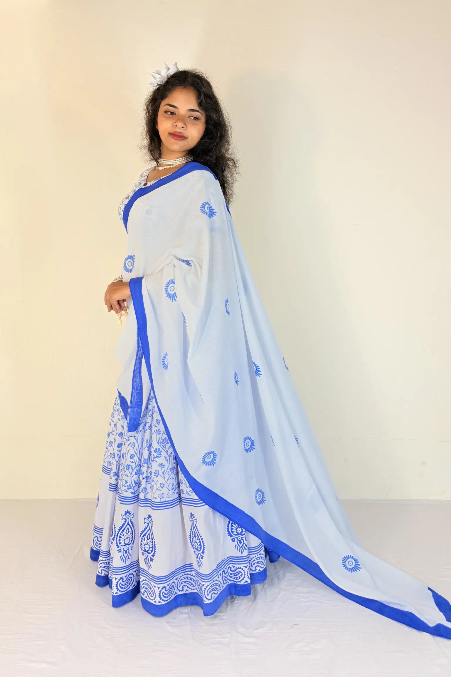 Woman wearing a light blue Gopi Dress with white patterns on a plain background