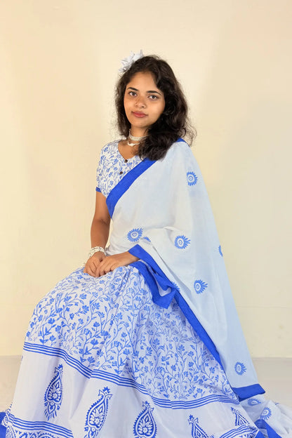 Woman wearing a white Gopi Dress with blue patterns against a beige background