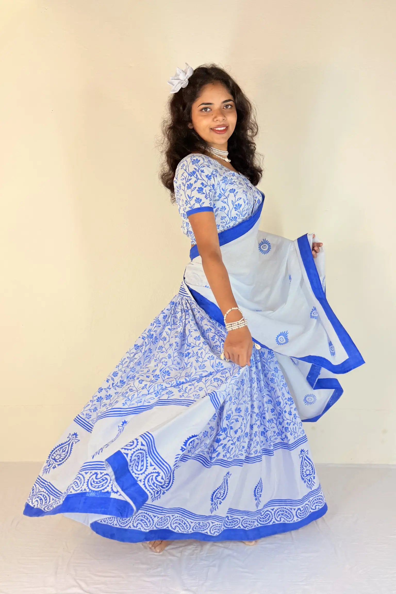 Woman wearing a blue and white traditional outfit with a matching dupatta against a plain background