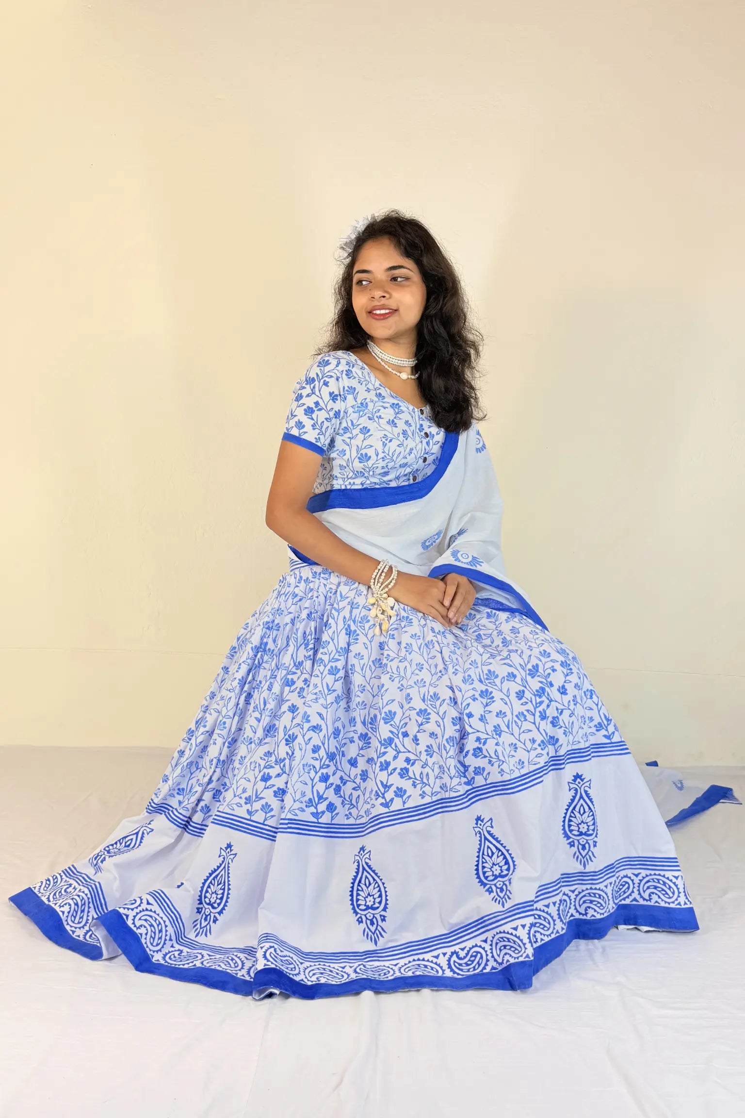 Woman wearing a blue and white traditional outfit with a plain background