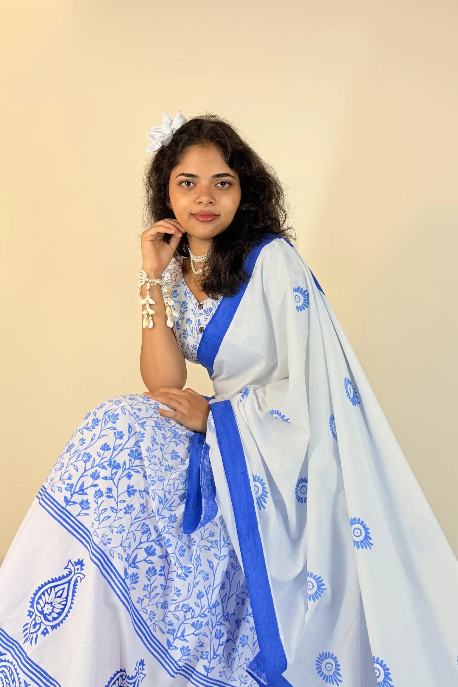 Woman wearing a white Gopi Dress with blue patterns against a beige background