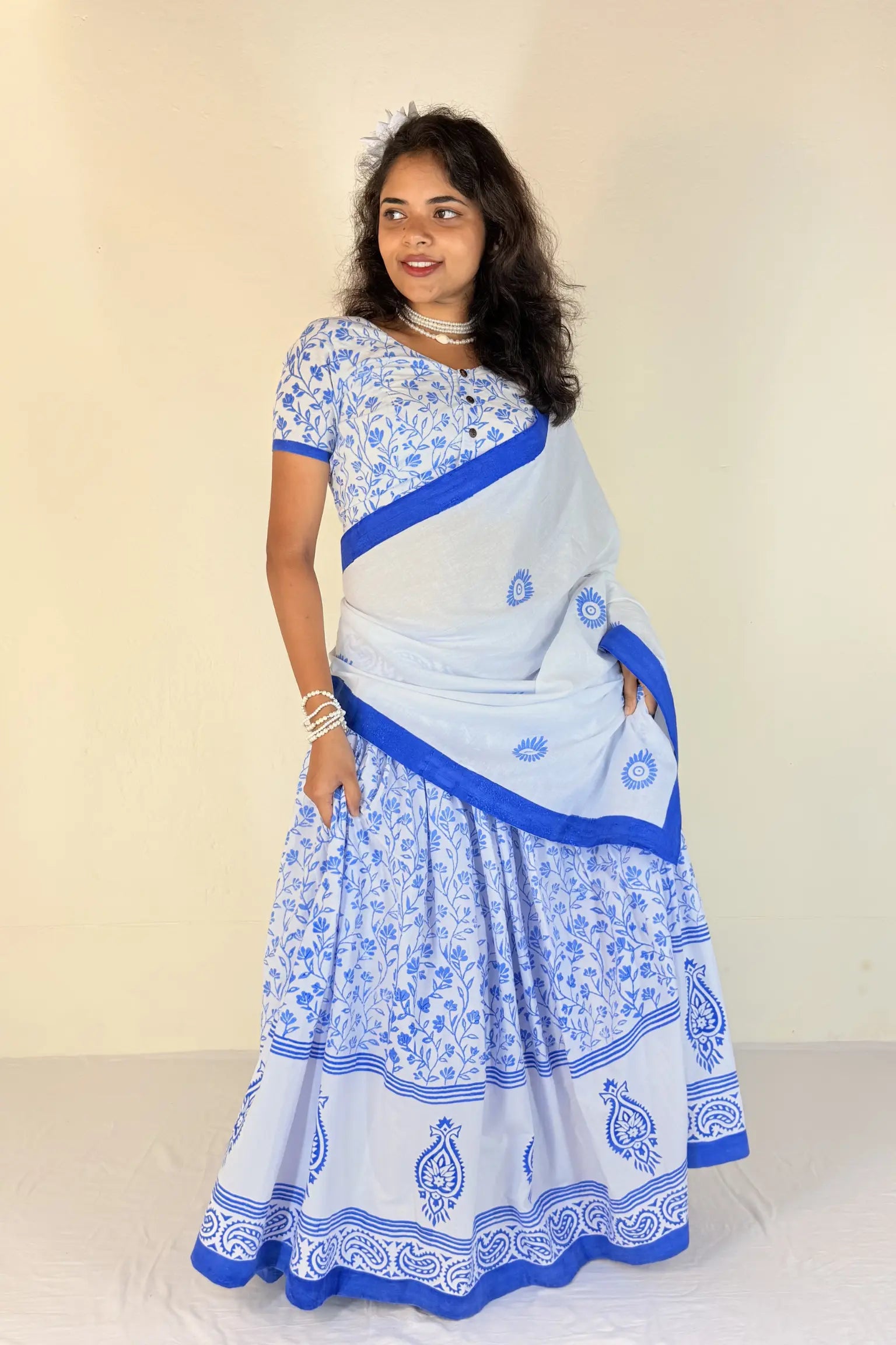 Woman wearing a white Gopi Dress with blue patterns against a plain background
