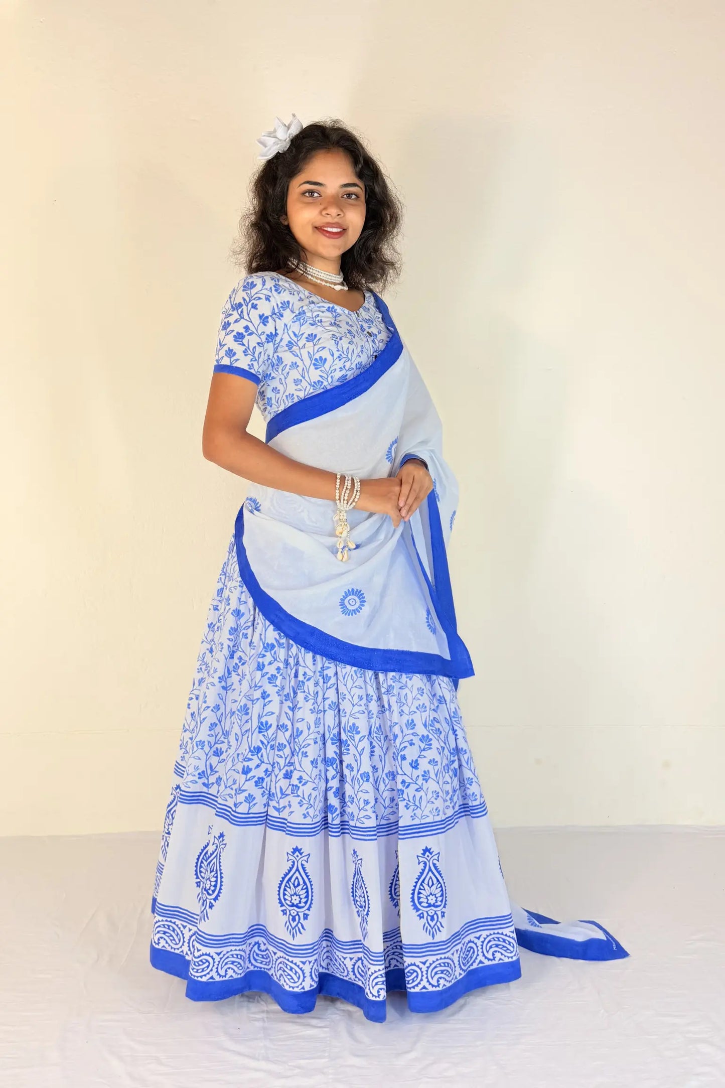 Woman wearing a blue and white traditional outfit with a plain background