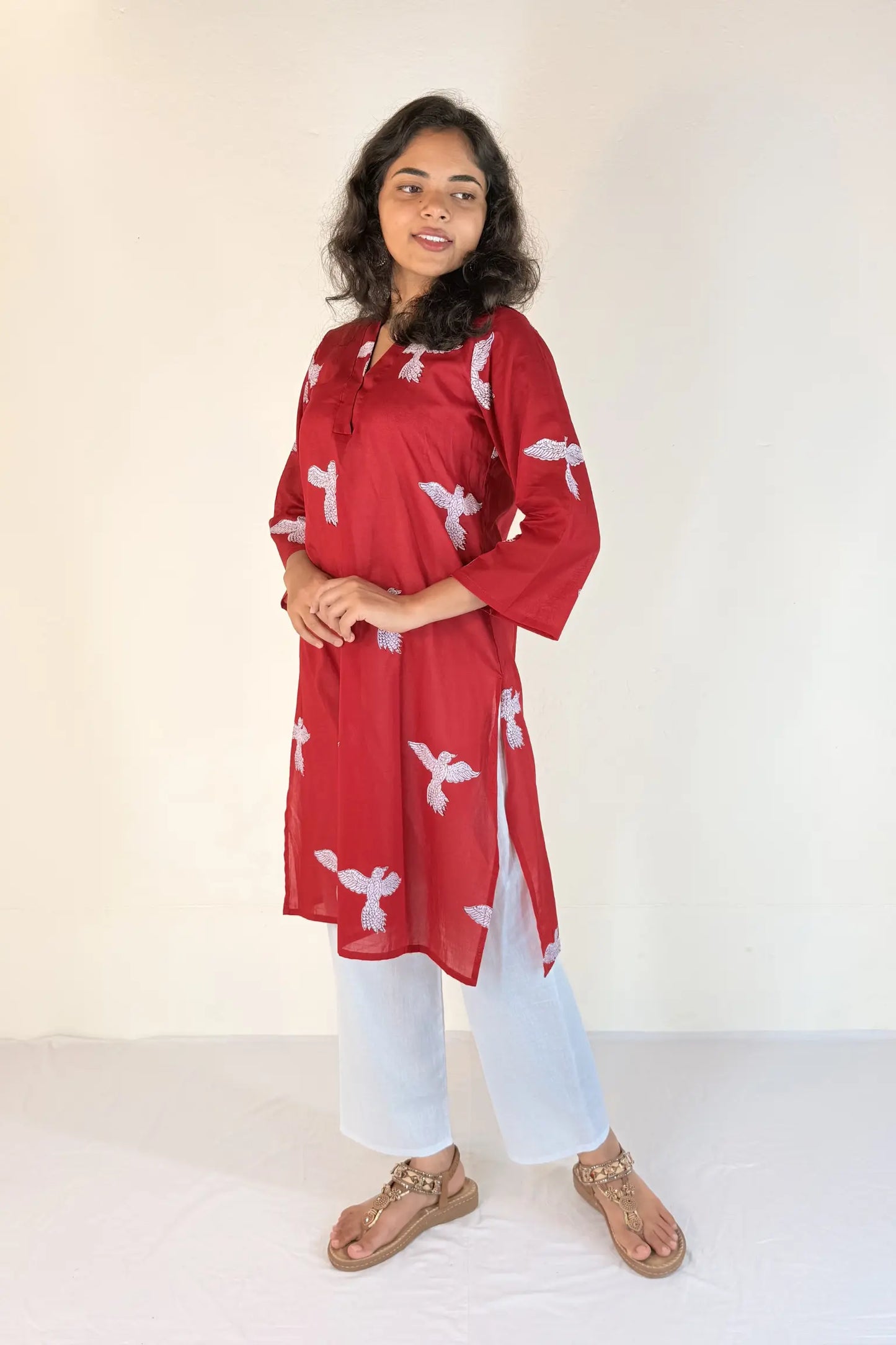 Woman wearing a pink outfit with white floral patterns on a plain background