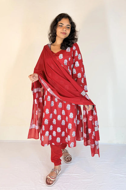 Woman wearing a red traditional outfit with white patterns on a plain background