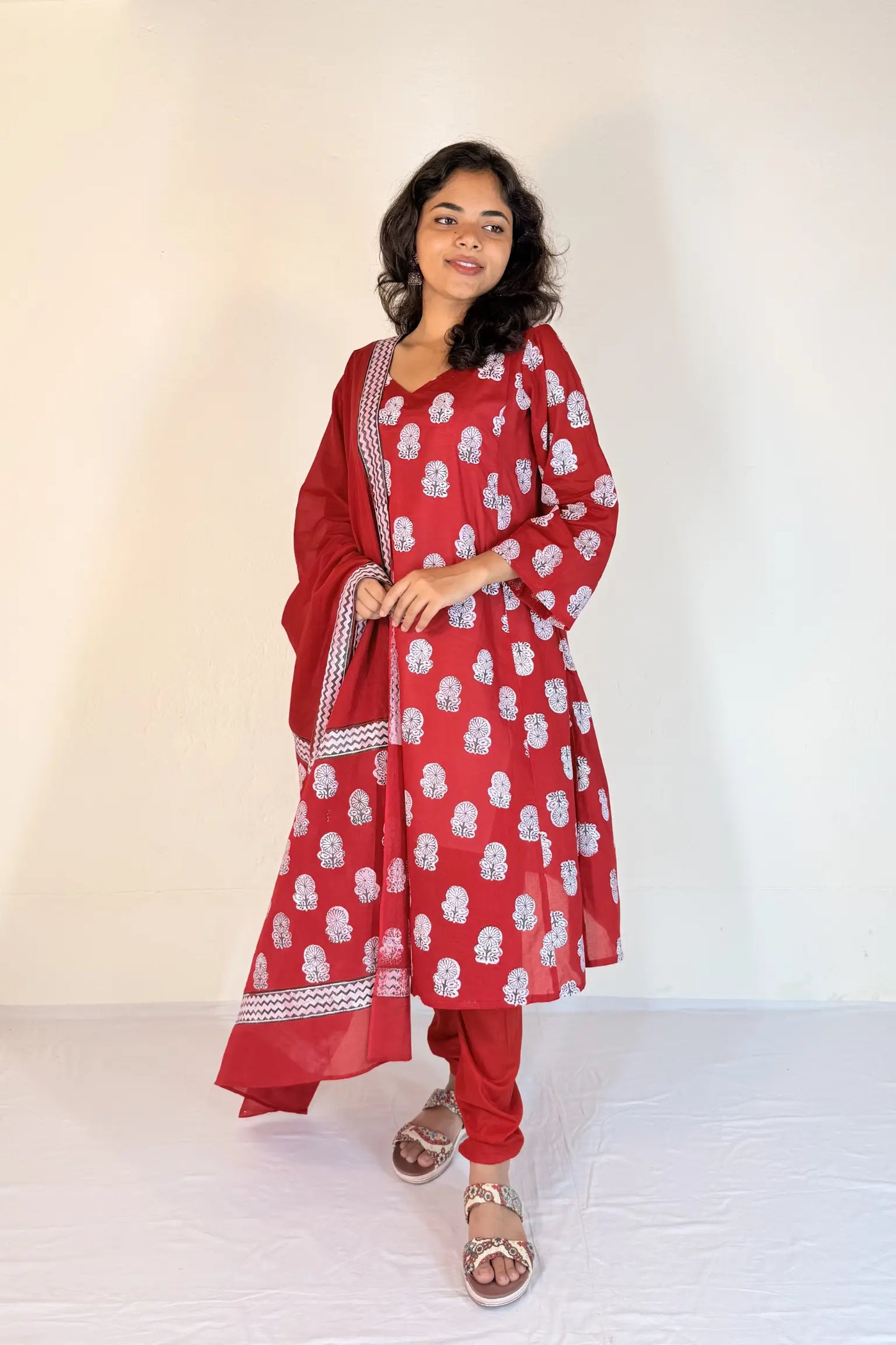 Woman wearing a red traditional outfit with white patterns on a white background