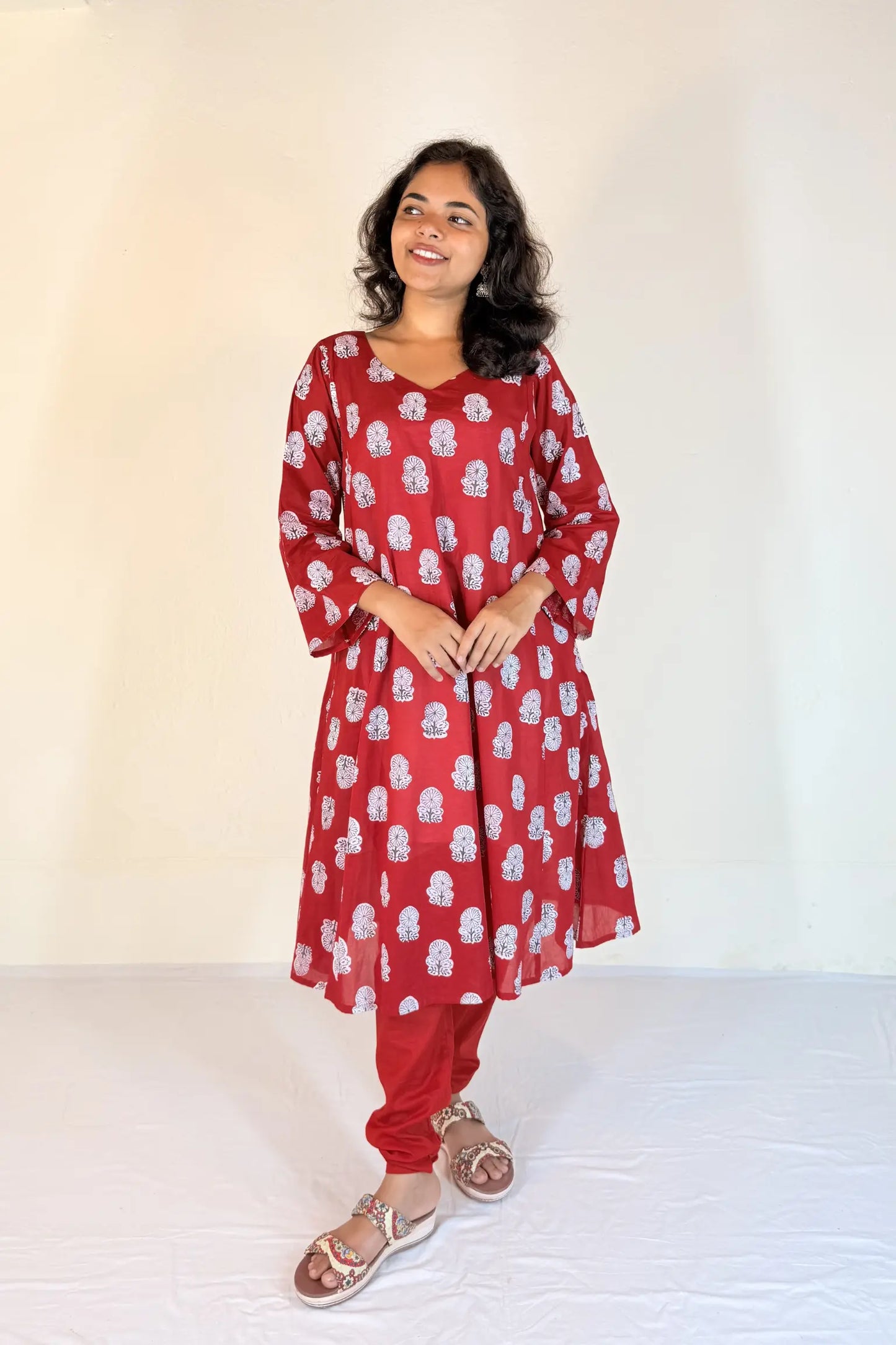 Woman wearing a red floral dress against a white background