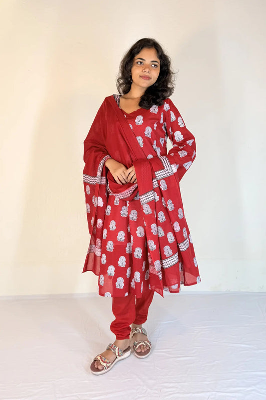 Woman wearing a red traditional outfit with white patterns on a plain background